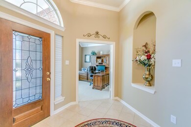 Spacious tiled foyer with art niches and crown molding.