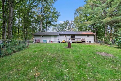Rear view of property featuring a wooden deck and view of scattered trees