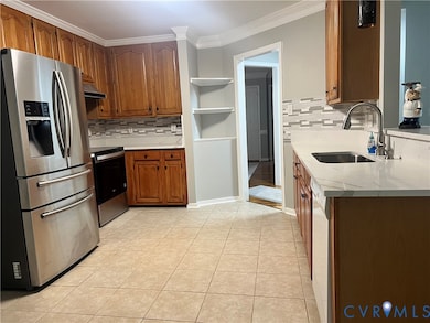Kitchen with appliances with stainless steel finishes, brown cabinets, crown molding, light stone countertops, and backsplash