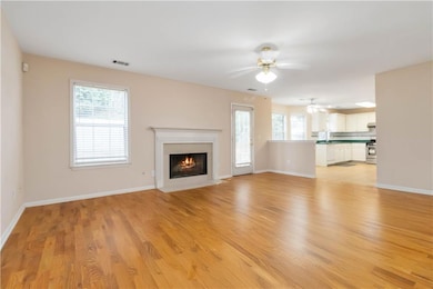 Unfurnished living room with a ceiling fan, plenty of natural light, a fireplace with flush hearth, and light wood-style floors