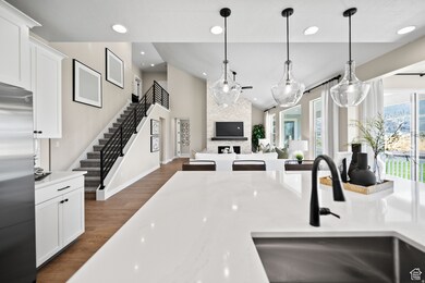 Kitchen with dark wood-style floors, pendant lighting, stainless steel refrigerator, white cabinets, and recessed lighting