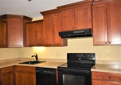 Kitchen has cherry wood cabinets.