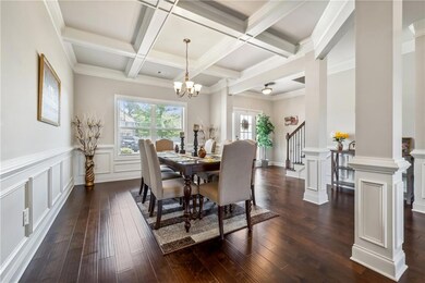 Dining space with beamed ceiling, dark wood finished floors, a decorative wall, coffered ceiling, and stairs