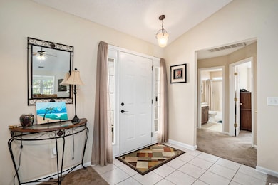 Entrance foyer with light tile patterned floors, lofted ceiling, light colored carpet, ceiling fan, and a textured ceiling