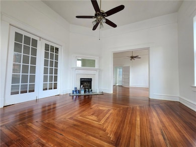 Unfurnished living room featuring a fireplace, ceiling fan, and parquet flooring