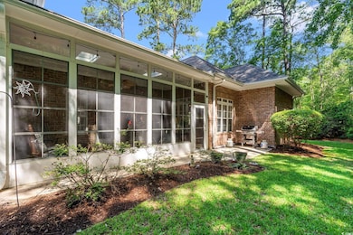 Back of house with brick siding, a sunroom, a lawn, a shingled roof, and a patio area