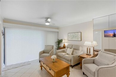 Living room featuring light tile patterned flooring, ornamental molding, and a ceiling fan