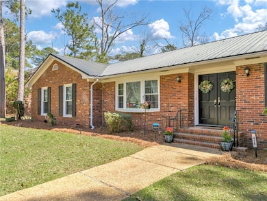 Ranch-style home with brick siding, metal roof, an