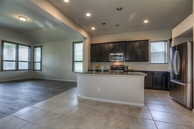 The kitchen has tall cabinets, granite countertops, a massive island with room for bar seating, and stainless appliances.