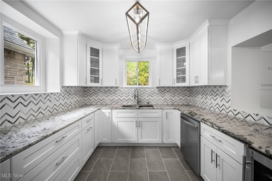 Main kitchen featuring glass insert cabinets, white cabinetry, light stone counters, and tasteful backsplash