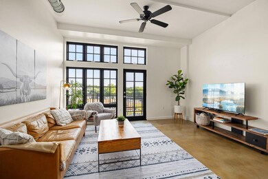 Living room with finished concrete flooring, ceiling fan, and a towering ceiling