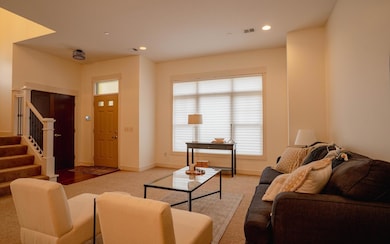 Great room with an open layout, freshly painted walls, and a large window that fills the space with natural light — perfect for relaxing or entertaining; with electric shades down.