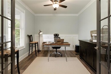Office with crown molding, a ceiling fan, dark woo