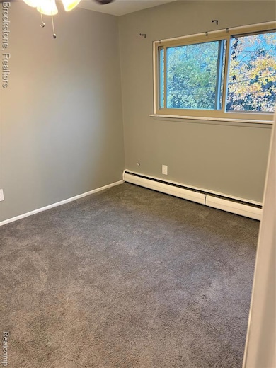 Empty room with baseboard heating, carpet floors, and ceiling fan