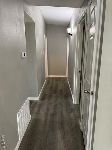 Hall with dark wood-type flooring and baseboards
