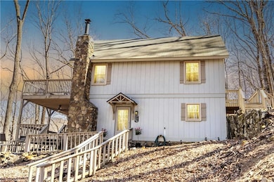 View of front facade featuring a wooden deck, a balcony, roof with shingles, and a chimney