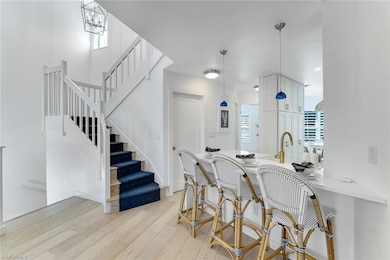 Kitchen featuring a breakfast bar area, light wood-style flooring, healthy amount of natural light, and decorative light fixtures