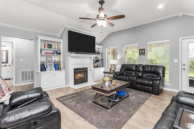 Living room with light wood-type flooring, ceiling fan, lofted ceiling, and ornamental molding