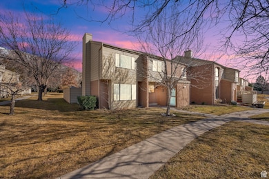 View of front facade with a yard, a chimney, and brick siding