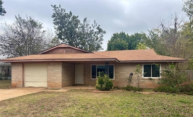 Single story home featuring a front lawn, driveway, an attached garage, brick siding, and a shingled roof