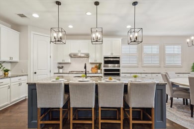 Kitchen with white cabinets, tasteful backsplash, a breakfast bar, recessed lighting, and hanging light fixtures