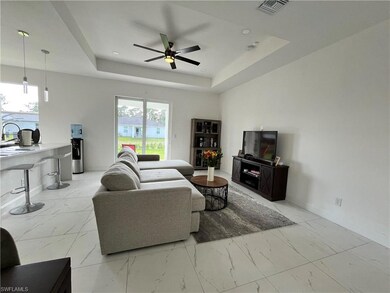 Living room with visible vents, baseboards, a raised ceiling, a ceiling fan, and marble finish floor