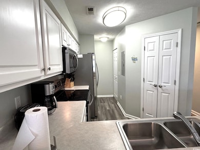 Kitchen with a textured ceiling, visible vents, st