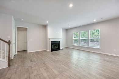 Unfurnished living room with recessed lighting, light wood-style flooring, stairs, and a fireplace with flush hearth