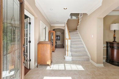 Entryway has tile flooring, crown molding and beautiful leaded glass door.