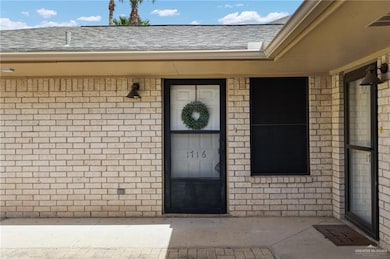 Entrance to property featuring brick siding and roof with shingles