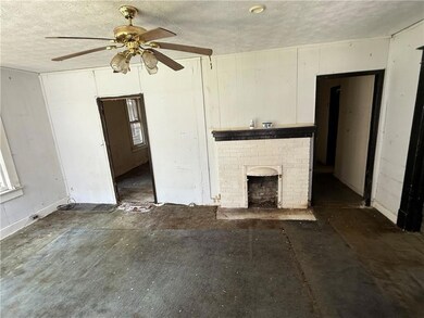 Unfurnished living room with a textured ceiling, ceiling fan, and a fireplace