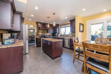 Kitchen featuring granite countertops, a center island with storage, dark brown custom cabinetry, hanging light fixtures, and a textured ceiling