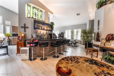 Bar with a high ceiling, a dry bar, visible vents,