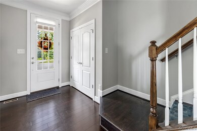 Foyer with coat closet, hardwood floors, crown mou