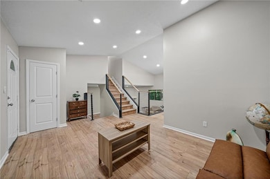 Living room featuring light wood-style floors, baseboards, stairway, recessed lighting, and vaulted ceiling