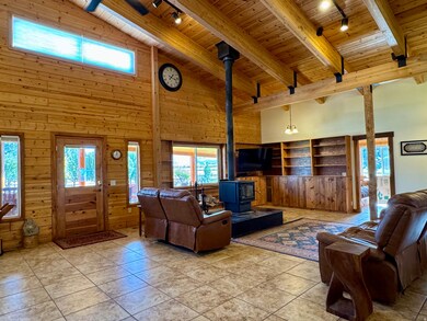 Tiled living room featuring track lighting, high vaulted ceiling, a wood stove, plenty of natural light, and a wood ceiling with exposed beams