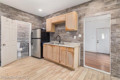 Kitchen with tile walls, light brown cabinets, freestanding refrigerator, light wood-style flooring, and recessed lighting