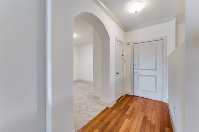 Foyer featuring arched walkways, ornamental molding, light wood finished floors, and light colored carpet