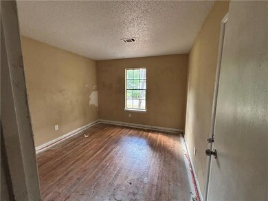 Empty room with wood finished floors, baseboards, and a textured ceiling