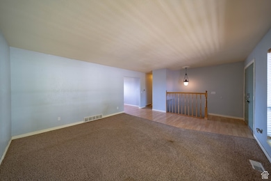 Unfurnished living room featuring carpet flooring and baseboards