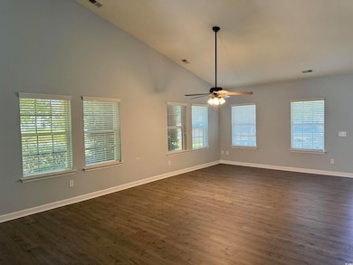 Spare room featuring dark wood-style flooring, a ceiling fan, high vaulted ceiling, and baseboards