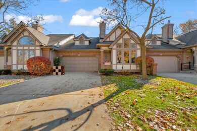Tudor house featuring brick siding, concrete driveway, a chimney, and a garage