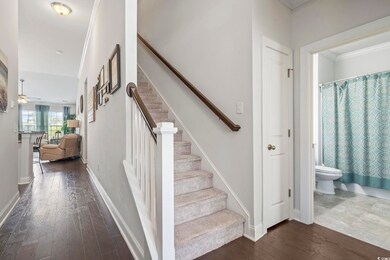 Stairway with wood finished floors, crown molding, and ceiling fan