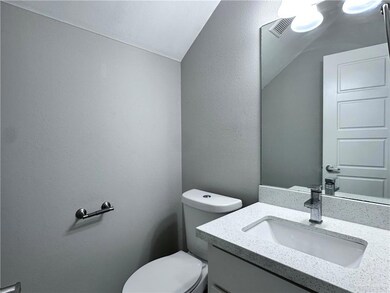 Bathroom featuring lofted ceiling, visible vents, toilet, and vanity