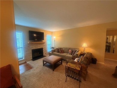 Carpeted living area with a stone fireplace and ba