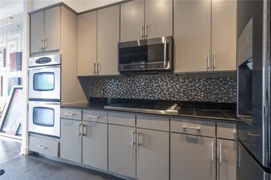 Kitchen featuring appliances with stainless steel finishes, dark countertops, gray cabinets, and decorative backsplash