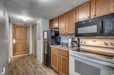 Kitchen with black appliances, sink, wood-type flo