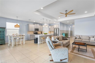 Living room featuring ceiling fan, light tile patterned flooring, a raised ceiling, and recessed lighting