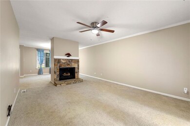 Unfurnished living room featuring ornamental molding, light colored carpet, a ceiling fan, and a fireplace