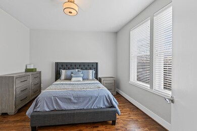 Bedroom with baseboards, multiple windows, and dar
